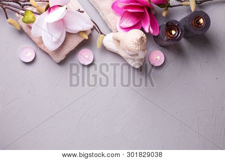 Burning Candles, Buddha, Towels  And Pink Magnolia Flowers On Grey Textured Background. Spa Concept.