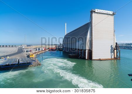 Hirtshal, Denmark - July 24, 2018: Ferry Boat Leaving The Harbor With A Drydock In The Background