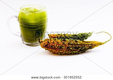 Raw Organic Bitter Melon Or Bitter Gourd With Its Extracted Juice In A Transparent Glass With Some I