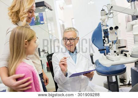 Likable eye specialist gives good eye glasses to child in eye clinic