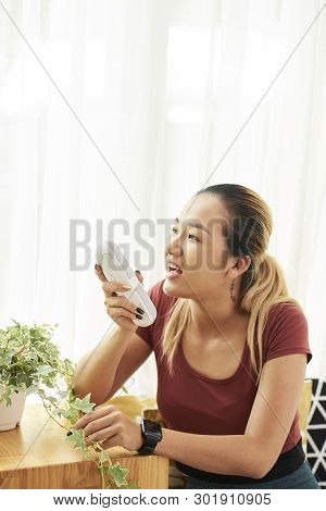 Positive Young Vietnamese Woman With Portable Speaker Singing A Song