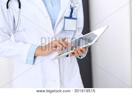 Doctor Woman Using Tablet In Clinic Office. Unknown Female Physician At Work While Standing Straight