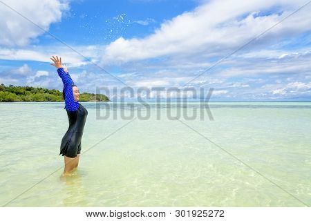 Happy Asian Teen Girl In A Swimsuit Play Splashing Water In The Sea With Fun Under The Blue Sky Of K