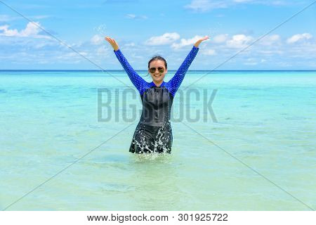 Happy Asian Teen Girl In A Swimsuit Play Splashing Water In The Sea With Fun Under The Blue Sky Of K