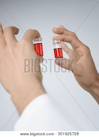 Hands Of Male Medic Or Researcher Hold Up Liquid Samples. Conccept For Card, Flyer Or Cover On The T