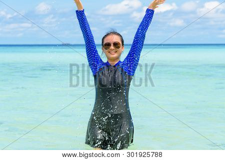 Happy Asian Teen Girl In A Swimsuit Play Splashing Water In The Sea With Fun Under The Blue Sky Of K