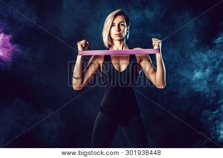 Sexy Woman In Sportswear Using A Resistance Band In Her Exercise Routine. Young Woman Performs Fitne