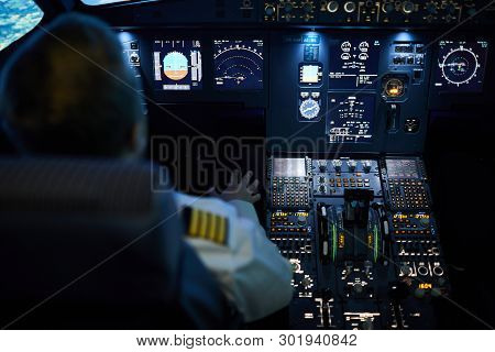 Rear View Of Unrecognizable Pilot Sitting At Control Panel With Radar Devices And Flight System Butt