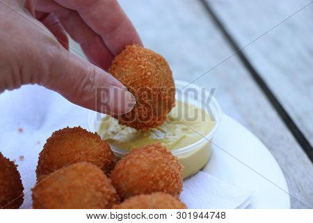Dutch Snack:  Woman Eating A Bitterbal With Mustard. Warm Stuffed Fried Meatballs, Often Served With