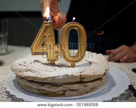 Hands Of A Woman Lighting Golden Candles Four And Zero Of A Birthday Cake Celebrating 40th Aniversar