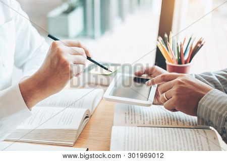 High School Or College Students Studying And Reading Using Tablet Together In Library