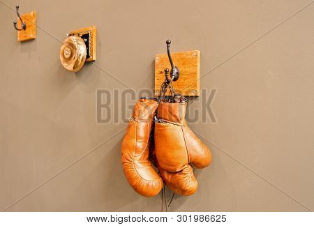 For All Your Boxing Needs. Pair Of Retro Sparring Boxing Gloves Hooked On Wall. Old Protective Sport