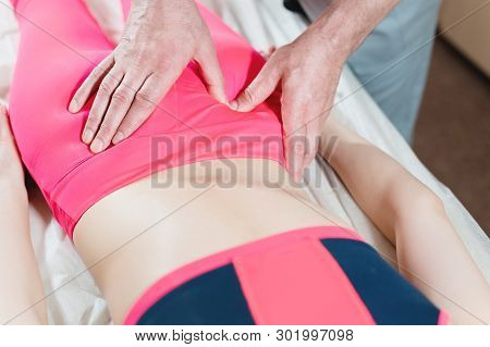 Close-up Of A Young Girls Spine Base Editing By A Male Physiotherapist Of Visceral Massage. The Hand