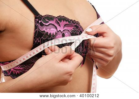 une jeune femme mesure sa poitrine avec un ruban à mesurer