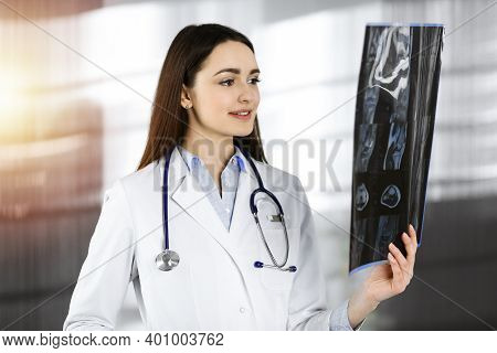 Professional Young Woman-doctor Is Looking At Her Patients Roentgenogram. Physician At Work In Sunny