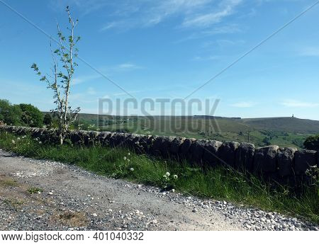 Roadside View Of The Calder Valley With A Country Land Surrounded By A Stone Wall With Stoodley Pike