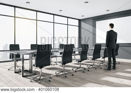 Businessman Working In Conference Interiror With Meeting Table And Blank Banner On Wall.  Workplace 