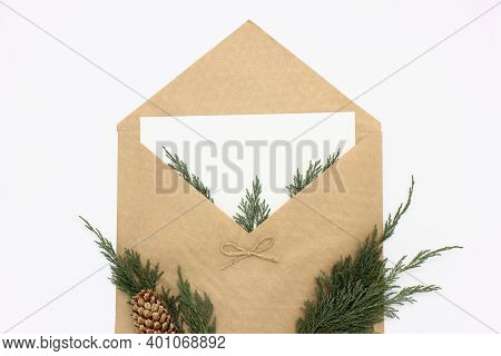 Open Christmas Envelope With A Blank Paper And Green Tuya Branches Inside. Flat Lay Composition Isol