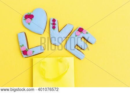 Inscription Love By Homemade Cookies And Yellow Package With Copy Space. Holiday Food Concept. Flat 