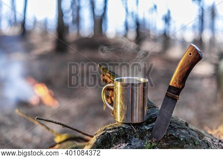 Tourist things - stainless camping cup of tea and special knife. Nature background.