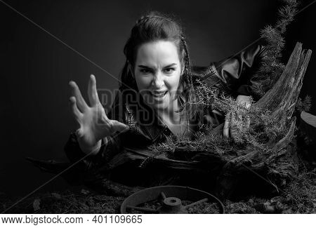 A Young Woman In A Black Leather Jacket Climbs Out Of The Pit Holding On To A Snag. Angry Girl Stret