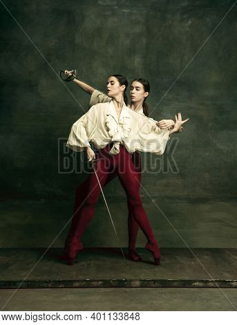 Flexibility. Two Young Female Ballet Dancers Like Duelists With Swords On Dark Green Background. Cau