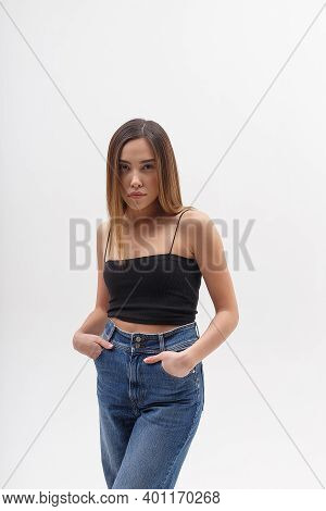 Portrait Of Young Attractive Asian Woman With Long Hair In Black Top, Blue Jeans Isolated On White S