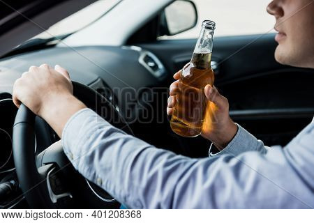 Cropped View Of Man With Bottle Of Whiskey Driving Car, Blurred Foreground.