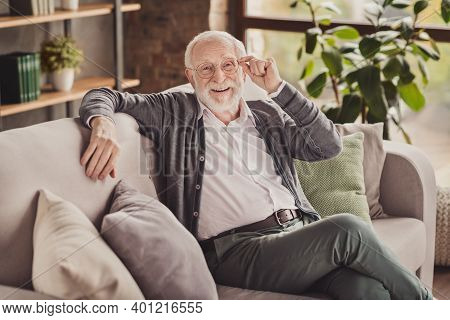 Photo Of Handsome Pensioner Wear Grey Cardigan Smiling Arm Glasses Sitting Couch Indoors House Flat