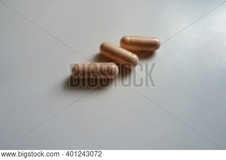 Closeup Of Three Pink Capsules Of Probiotic Dietary Supplement