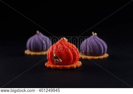 Closeup View Of Matte Purple And Orange Dessert Isolated On Black Studio Background. Three Small Squ