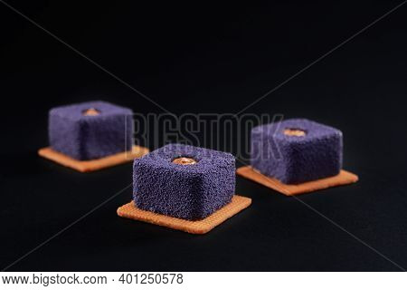 Closeup View Of Matte Purple Pie Pieces Filled With Brown Creme Isolated On Black Studio Background.