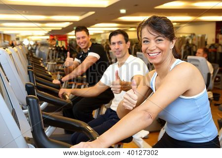 Zwei Mann und eine Frau auf Heimtrainer Showing Thumbs Up