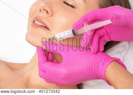 Cosmetologist Makes Lipolytic Injections To Burn Fat On The Chin, Cheeks And Neck Of A Woman Against
