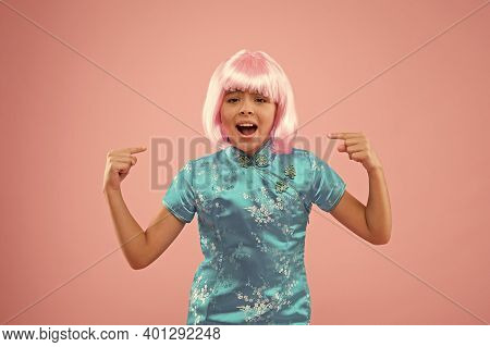 Look At This. Unhappy Girl Pointing Fingers At Wig. Small Child Pointing Pink Background. Fashion An