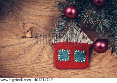 Concept Of Christmas.knitted House And Pine Branch On Wooden Ba