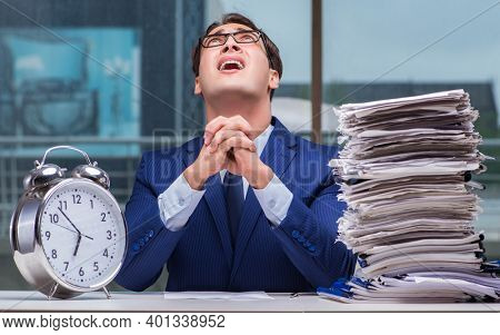 Businessman with pile stack of paper paperwork and an alarm cloc