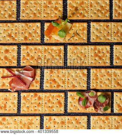 Conceptual Slices Of Salami, Cheese And Smoked Bacon On Crackers With Salt