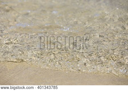 Clean Clear Water On The Beach. Bumpy Waves Are Picked Up By The Wind. White Foam From Bubbles Of Di