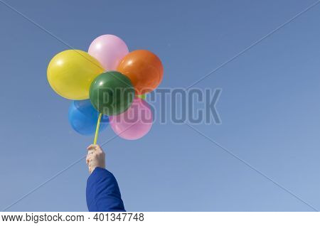Hand Holdind Flying Helium Baloons Against Bright Blue Sky. Copy Space.