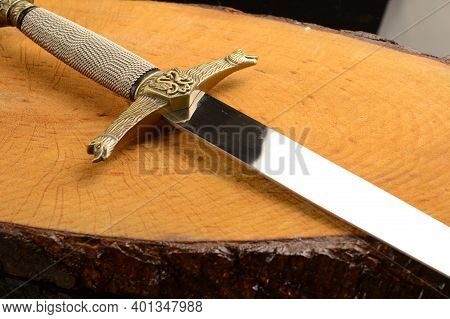 A Closeup View Of A Dagger On A Piece Of Freshly Cut Wood.