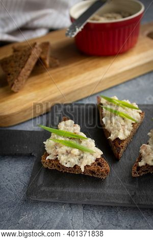 Canapes Or Toasts With Herring And Rye Bread Forshmak With Green Onions On A Black Tapas Board. Back