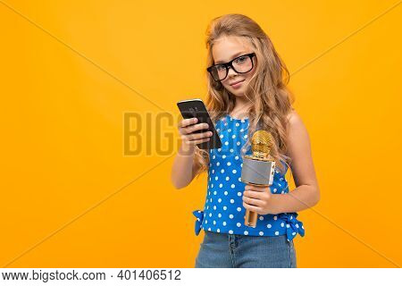 Portrait Of Young Caucaian Girl With Long Fair Hair In Black Glasses With A Microphone Interwiews An