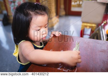 Asian Baby Child Girl Is Using A Hand To Hold A Banknote To Put In A Box To Donate Or Make Merit In 