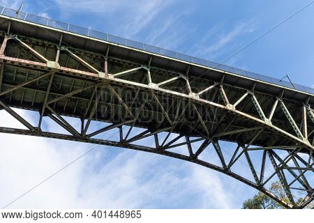 Arch Bridge Seen From Below, Rusting Metal Trusswork, Blue Sky With White Clouds, Horizontal Aspect