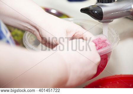 Woman Washing Dishes With A Pink Cleaning Rag