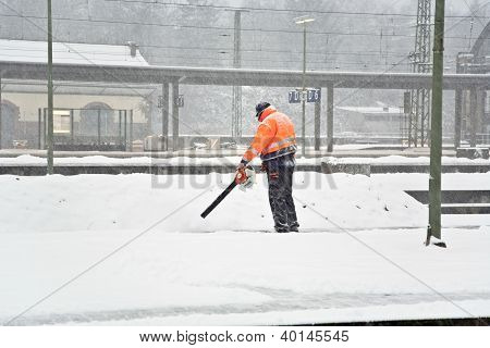 WIESBADEN, GERMANY - JAN 3, 2011: worker is cleaning the platform of a train station from snow
