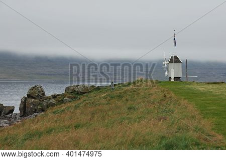 Windmill And Icelandic Flag In Vigur Island In A Cloudy And Windy Day, Iceland
