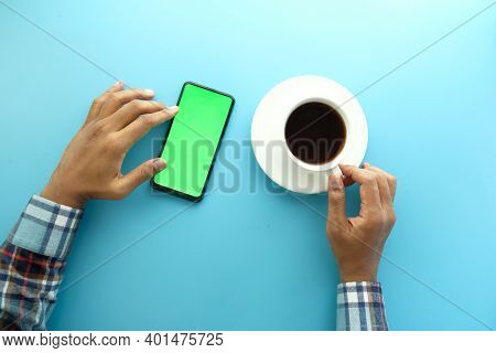Top View Of Man Hand Using Smart Phone And Drinking Tea
