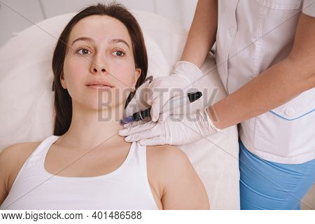 Lovely Woman Receiving Skincare Treatment By Beautician, Using Dermapen. Mesotherapy Concept